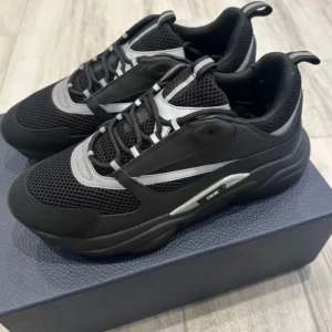 B22 dior  - Snygga svarta sneakers från Dior med grå detaljer och snörning. Skorna har en modern design med en robust sula och meshmaterial för extra komfort. Perfekta för en stilren look. Kvitto box allt finns 