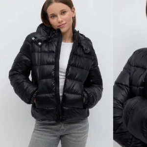 Svart pufferjacka - Snygg svart pufferjacka med dragkedja och hög krage. Jackan har en quiltad design och långa ärmar, perfekt för kyligare dagar. Den är både stilren och praktisk med fickor framtill.