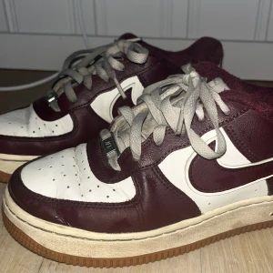 Nike Air Force  - Snygga Nike Air Force sneakers i en stilren kombination av vinrött och vitt. Skorna har klassisk snörning och en robust sula för extra komfort. Perfekta för en casual look. Nu tvättade så är blöta och dom är lite sönder