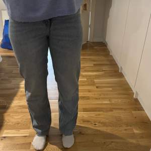 Säljer ett par klassiska blå jeansbyxor med en rak passform. Byxorna har en normal midja och är perfekta för en avslappnad stil. De har en traditionell femficksdesign och stängs med dragkedja och knapp.
