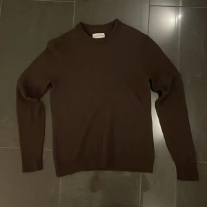 Brun merinoulltröja från These Glory Days - Säljer en stilren brun tröja från These Glory Days i mjuk och lyxig merinoull. Perfekt för kyliga dagar med sin klassiska design och långa ärmar.har använt den en gång. Ett måste i garderoben för den som älskar kvalitet och komfort.