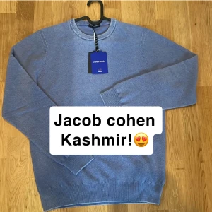 Blå kashmirtröja från Jacob Cohen - Säljer en lyxig blå  heavy weight 100% kashmirtröja från Jacob Cohen. Tröjan har en klassisk rund halsringning och långa ärmar med ribbade muddar. Helt ny med tags. Perfekt för en stilren och bekväm look. Retail: 7000kr.