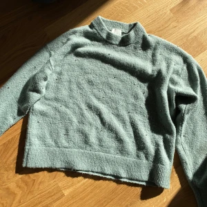 Grön stickad tröja från H&M - Säljer en mysig grön stickad tröja från H&M. Tröjan har långa ärmar och små söta pärldetaljer ! ✨💚