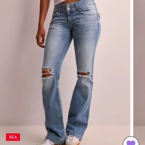 Ljusblå bootcut jeans med slitningar - Säljer ett par ljusblå bootcut jeans med slitna detaljer över knäna. Jeansen har klassisk femficksdesign, knapp- och dragkedjegylf samt en snygg tvätt. Uppsyda. Perfekta för en avslappnad och trendig look.