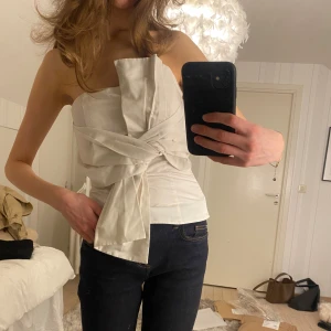 Vit korsettopp med knytning - Jättefin och populär vit topp med rosett från H&M. Populär och slutsåld. Använd en gång. Normal i storleken. 