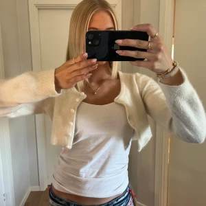 Stickad kort kofta - Super fin krämvit kofta, köpt här på Plick men har tyvärr inte kommit till användning. Bra skick, men ett fåtal noppor på ärmarna som man enkelt kan ta bort. Billigt pris.