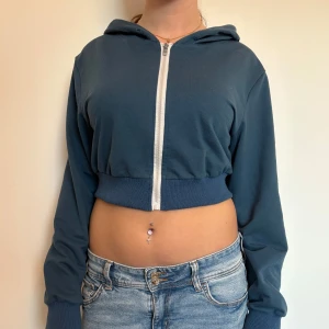 Blå croppad hoodie med dragkedja - Bra skick! Fin att ha som den är eller som en kofta över ett linne.