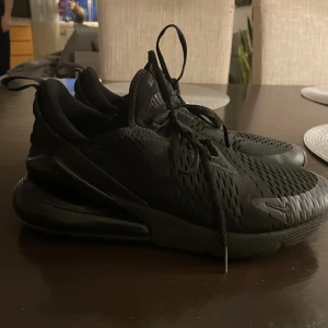 Nike 270 sneakers - Säljer ett par svarta Nike sneakers 270 med snörning och en stilren design. Skorna har en luftig ovandel och en bekväm sula, perfekt för vardagsbruk. De är i storlek herr 44 och har en modern look som passar till det mesta.