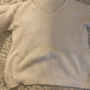 Beige stickad tröja med v-ringning - Säljer en mysig beige stickad tröja med v-ringning. Tröjan har långa ärmar och ribbstickade muddar vid ärmslut och nederkant. Perfekt för kyliga dagar!❤️