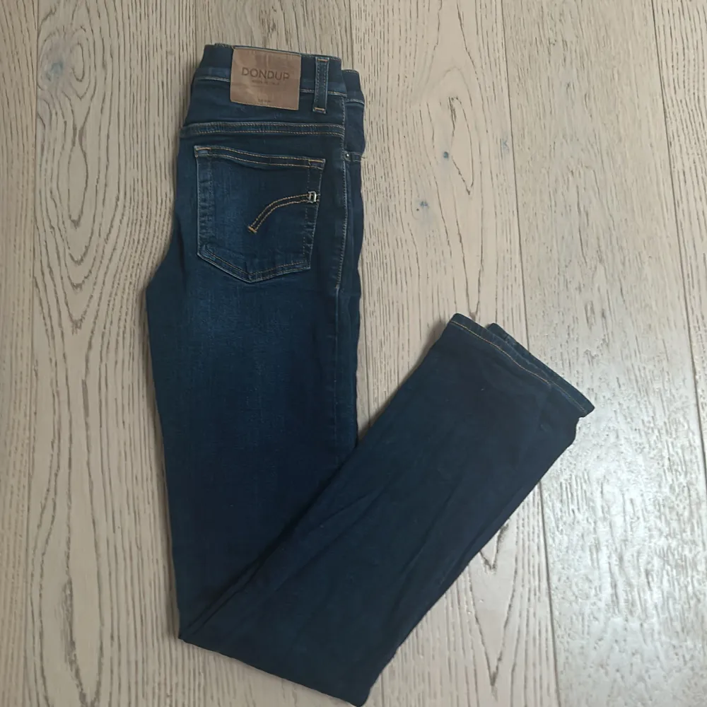 Snygga mörkblå jeans från Dondup med klassisk femficksdesign och subtila slitningar. De har en knappgylf och är perfekta för en stilren look. Typ som ny skick. Farkut & Housut.