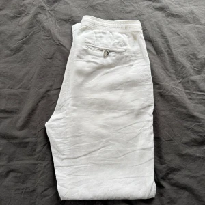 Vita linnebyxor från Morris - Snygga vita linnebyxor från Morris med en stilren design. Byxorna har en knappdetalj på bakfickan och är perfekta för en avslappnad men elegant look. Tillverkade i linne för en luftig och bekväm känsla. Nypris 1899kr!