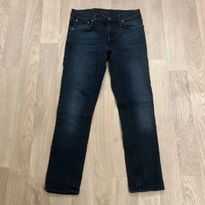 Mörkblå jeans från Nudie Jeans - Snygga mörkblå jeans från Nudie Jeans med en klassisk femficksdesign. De har en normal passform och är tillverkade i slitstarkt denim. Perfekta för en stilren look. Tveka inte vid att ställa frågor