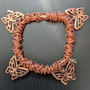 Kopparfärgat armband med fjärilar - Unikt armband i kopparfärg med intrikat design av fjärilar. Armbandet har en spiralformad struktur som ger det en bohemisk känsla. Perfekt för att lägga till en touch av naturinspirerad elegans till din stil.