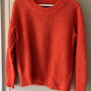 Orange stickad tröja - Säljer en härlig orange stickad tröja med rund halsringning. Tröjan är tillverkad av en blandning av alpacka och återvunnen polyester, vilket gör den både mjuk och hållbar. Perfekt för kyliga dagar!