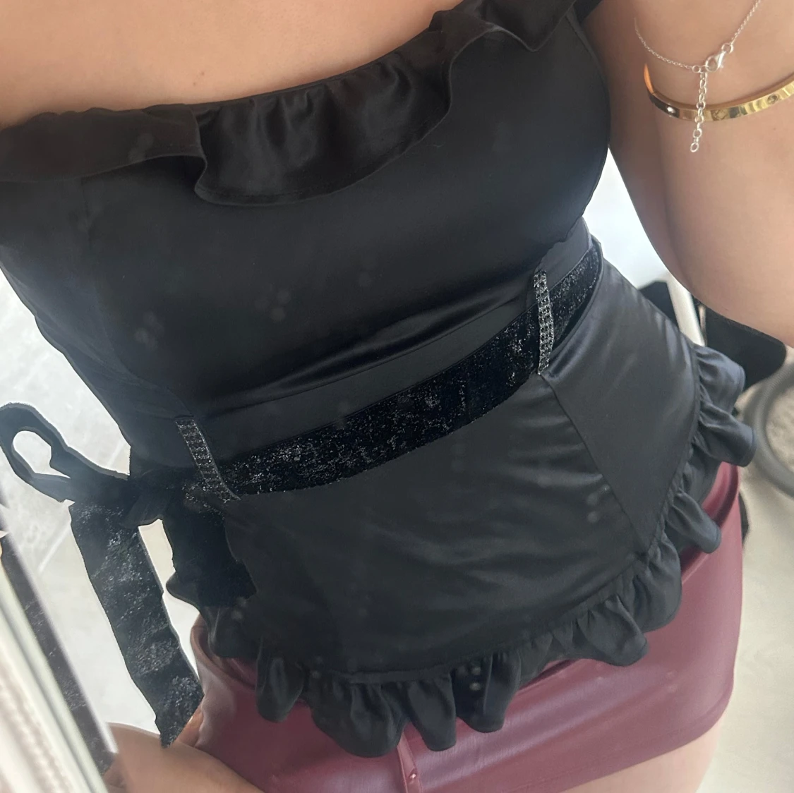 Svart axelbandslös topp med volangdetaljer