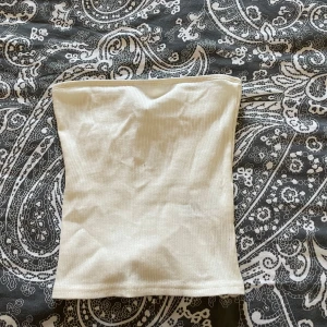 Vit ribbad tubtopp från H&M Divided - Säljer en stilren vit ribbad tubtopp från H&M Divided. Den är väldigt fin på men kommer tyvärr inte till användning mer💗