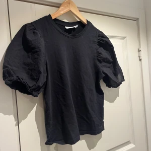 Svart topp med puffärmar från Vila - Snygg svart topp från Vila med puffiga kortärmar som ger en trendig look. Perfekt för att lyfta vilken outfit som helst. 