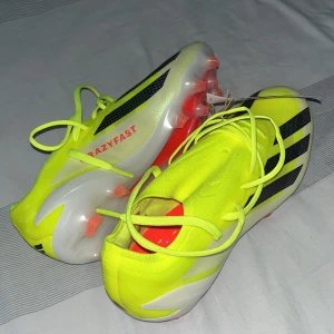 fotbollsskor - Säljer ett par gula Adidas fotbollsskor med svarta detaljer och snörning. Skorna har en modern design med texten 'CRAZYFAST' på sidan och är perfekta för snabba spelare på planen. HELT NYA KÖPT FÖR 2499kr