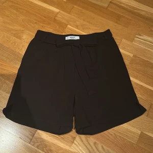 Svarta shorts från Object - Snygga svarta shorts från Object med knytband i midjan. Perfekta för en stilren look. De har en lös passform och är tillverkade i ett mjukt material.
