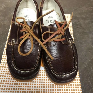 Bruna skinn loafers seglarskor  med snörning 33  - Snygga bruna loafers i skinn med dekorativ snörning framtill. Perfekta för en stilren look och bekväma att bära hela dagen. Passar både till vardag och mer uppklädda tillfällen.