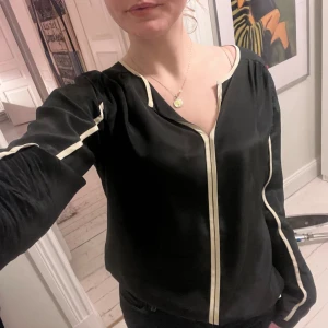 Silkblus med beiga detaljer - Fin svart blus med beiga detaljer i 100% silke från M.Wiesneck i nyskick i storlek 38