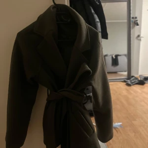 Olivgrön kappa med bälte -  olivgrön kappa i bra skick från gina tricot