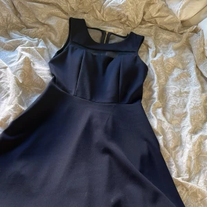 Marinblå ärmlös klänning med dragkedja - Elegant svart klänning med rund hals och transparenta mesh-detaljer vid axlarna. Klänningen är ärmlös och har en guldig dragkedja i ryggen. Knappt använd💕 inte de bästa bilderna men kan skicka bättre haha