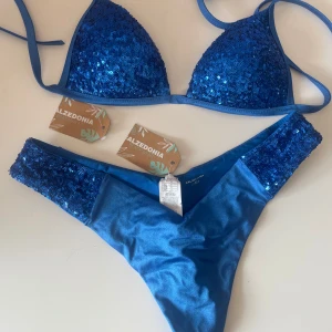 Blå paljett bikini från Calzedonia - Snygg blå bikini från Calzedonia som är oanvänd med prislapparna kvar. Överdelen har knytband och trekantsformade kupor. Perfekt för en dag på stranden eller vid poolen!👙☀️        Skriv gärna vid funderingar eller frågor💞