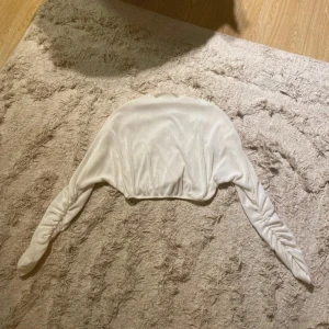 Vit ribbad bolerotopp från Bianca x Nelly - Säljer en stilren vit bolerotopp från Bianca x Nelly. Toppen är ribbad och har långa ärmar, perfekt för att lägga till en extra touch till din outfit.