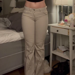 Beige bootcut byxor - Snygga beige bootcut byxor med låg midja. Byxorna har en klassisk design med fickor både fram och bak. Perfekta för en stilren look.