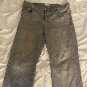 Jeans Zara  - Snygga grå jeans från Zara med femficksdesign och raka ben. Jeansen har en tvättad look och är tillverkade i bomull.