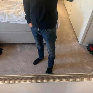 Replay Anbass jeans herr, mörkblå - Säljer ett par snygga Replay Anbass jeans i mörkblå tvätt med diskreta slitningar. Klassisk femficksmodell, raka ben och normal passform. Jeansen är tillverkade i bomull med lite stretch för extra komfort. Perfekta för dig som gillar stilrena och bekväma jeans. Storlek 30/32