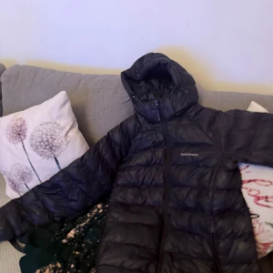 Svart dunjacka från Peak Performance - Denna jacka är precis som ny används inte jätte snygg. Folk som tar xs/s får plats i den. Säljer en svart dunjacka från Peak Performance med huva och dragkedja. Jackan är quiltad och har en stilren look med logga på bröstet och huvan. Perfekt för kalla dagar och enkel att matcha med allt.
