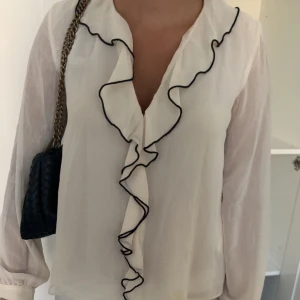 En stilren blus med volanger och svarta detaljer - Jag säljer en stilren blus från Zara med volanger och svarta detaljer som ger en så sjukt cool touch . Inga defekter och passar till allt! 