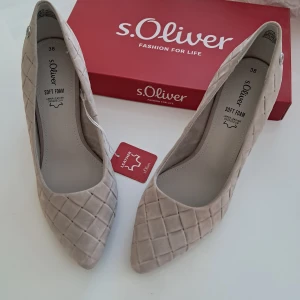 Beige pumps i läder från s.Oliver - Stilrena pumps från s.Oliver i beige läder med quiltat rutmönster. Skorna har spetsig tå och hög klack, vilket ger en elegant look. Mjukt innersula med soft foam för extra komfort. Perfekta för dig som gillar klassisk men trendig stil.