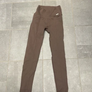 Bruna leggings från Aim'n - Snygga bruna leggings från Aim'n med hög midja och diskret struktur i tyget. De är tighta och stretchiga, perfekta för träning eller chill. Materialet är syntet och ger en skön passform som sitter på plats hela dagen. Går att diskutera pris