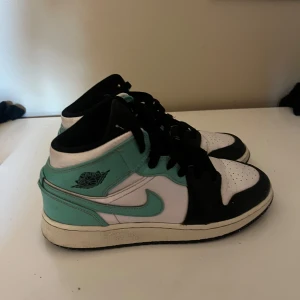 Nike Air Jordan 1 Mid Mint/svart/Vit - Snygga Nike Air Jordan 1 Mid sneakers i mintgrönt, svart och vitt skinn. Använd ganska många gånger men fortfarande i bra skick. Köpte dom för 1500kr. 