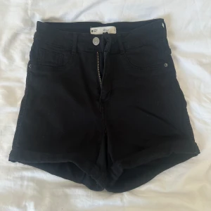 Svarta jeansshorts Gina Tricot - Svarta Molly jeansshorts från Gina Tricot. Klasssisk femficksdesign. De har uppvikta benslut, bälteshällor och dragkedja framtill. Perfekta för sommardagar och enkla att matcha med allt. Snygg och tidlös modell som alltid funkar