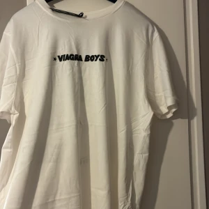 Viagra Boys vit t-shirt XL - Vit t-shirt från Viagra Boys i storlek XL med svart tryck på bröstet och en stor, unik grafisk illustration på ryggen. Klassisk passform med rund hals och korta ärmar. Tillverkad i mjuk bomull, perfekt för dig som gillar bandmerch och coola prints. Aldrig använd 