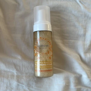 Lumene Cleansing Foam - Lumene Kirkas Radiance Boosting Cleansing Foam i genomskinlig plastflaska med vit pump. Innehållet är ljusgult och flaskan har orange och vita blommor på etiketten. Perfekt för normal hud och ger en fräsch känsla vid rengöring.