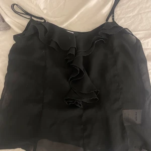 Svart volangtop - Säljer en svart linnetopp från Bik Bok. Den är gjord i ett tunt tyg. Väldigt fint skick❤️
