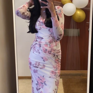 Lång blommig klänning  - Superfin långklänning i vit rosa. Endast använd en gång på en fest, är i mycket bra skick. Den köptes för 325 kr o jag säljer den för 200