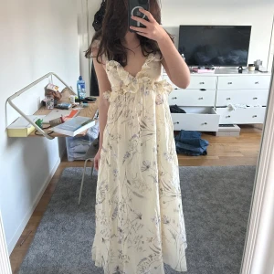 Blommig långklänning med volangdetaljer (intressekoll) - Intressekoll på denna klänning! Klänningen har volangdetaljer och en öppen rygg med knytning. Perfekt för sommaren 💞💞💞den passar flera storlekar då den är stretchigt där bak. Endast använd en gång! 