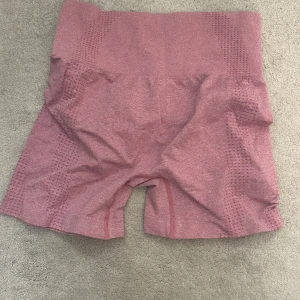 Rosa seamless träningsshorts M - Säljer ett par rosa seamless träningsshorts i storlek M. De är högmidjade och har en tight passform med ventilerande mesh-detaljer längs sidorna. Perfekta för gymmet eller löpning, stretchiga och bekväma med snygg sportig look.