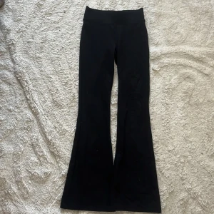 Svarta bootcut byxor Gina Tricot - Svarta bootcut byxor från Gina Tricot med hög midja och stretchigt material. Snygg passform med utsvängda ben, perfekta till sneakers eller boots. Stilrena och enkla att matcha med allt i garderoben.
