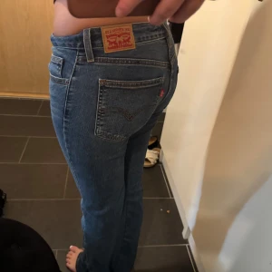 Levi's Superlow Bootcut jeans blå - Säljer ett par klassiska Levi's Superlow Boot jeans i blå denim. De har låg midja och bootcut-ben, perfekt för dig som gillar en retro vibe. Jeansen har fem fickor, snygga kontrastsömmar och ikonisk Levi's-lapp bak. Materialet är slitstarkt bomullsjeans.
