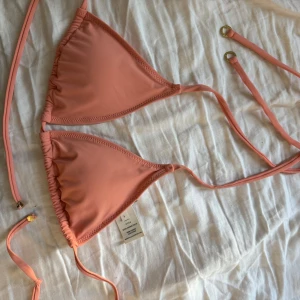 Stella McCartney - Säljer super fin koral färgad bikiniöverdel med guld detaljer från Stella McCartney 