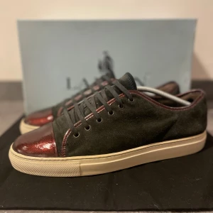 Lanvin sneakers - Säljer dessa riktigt feta och unika sneakers från Lanvin. Dem har en svart marinblå mocka i hög kvalitet samt en riktig fin vinröd toecap. Dessa Lanvins är rätt så sällsynta! Storlek 45, Bra skick! Box medföljer såklart! Nypriset ligger på runt 5000 kr +. Dessa skor är perfekta för en riktigt fin outfit eller kostym. Passar i princip till alla outfits! Hör av er ifall ni vill ha fler bilder eller ifall ni har några frågor! 💬 Mvh. Shoeasy ⚜️