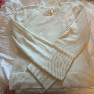 Beige stickad tröja med vida ärmar H&M - Supermysig beige stickad tröja från H&M med breda ribbade muddar och vida ärmar. Enkel och clean look med rund halsringning, perfekt att styla med kjol eller jeans. Tröjan är i mjukt material och har en relaxed fit.