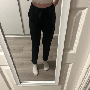 Svarta byxor med knytband - Snygga svarta byxor med hög midja och knytband i midjan. Byxorna har en loose passform och är tillverkade i ett mjukt material som ger en bekväm känsla. De är använda och lite noppriga